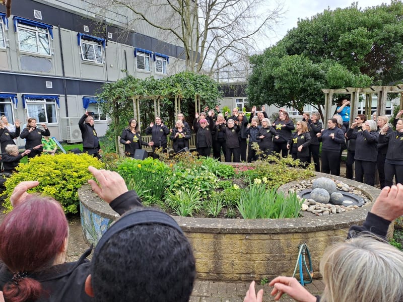 Rock Choir Oxfordshire gathering in a circle in Witney Community Hospital garden